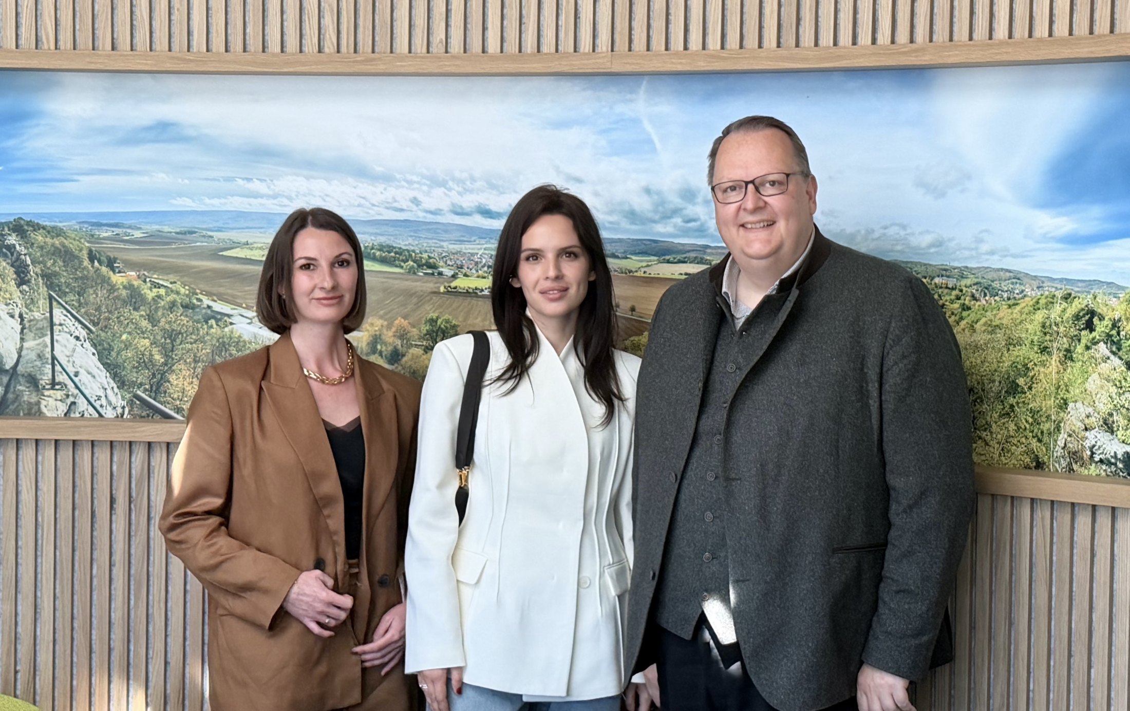 Anna Bon with two others in Blankenburg town hall, in front of a panorama of the Harz