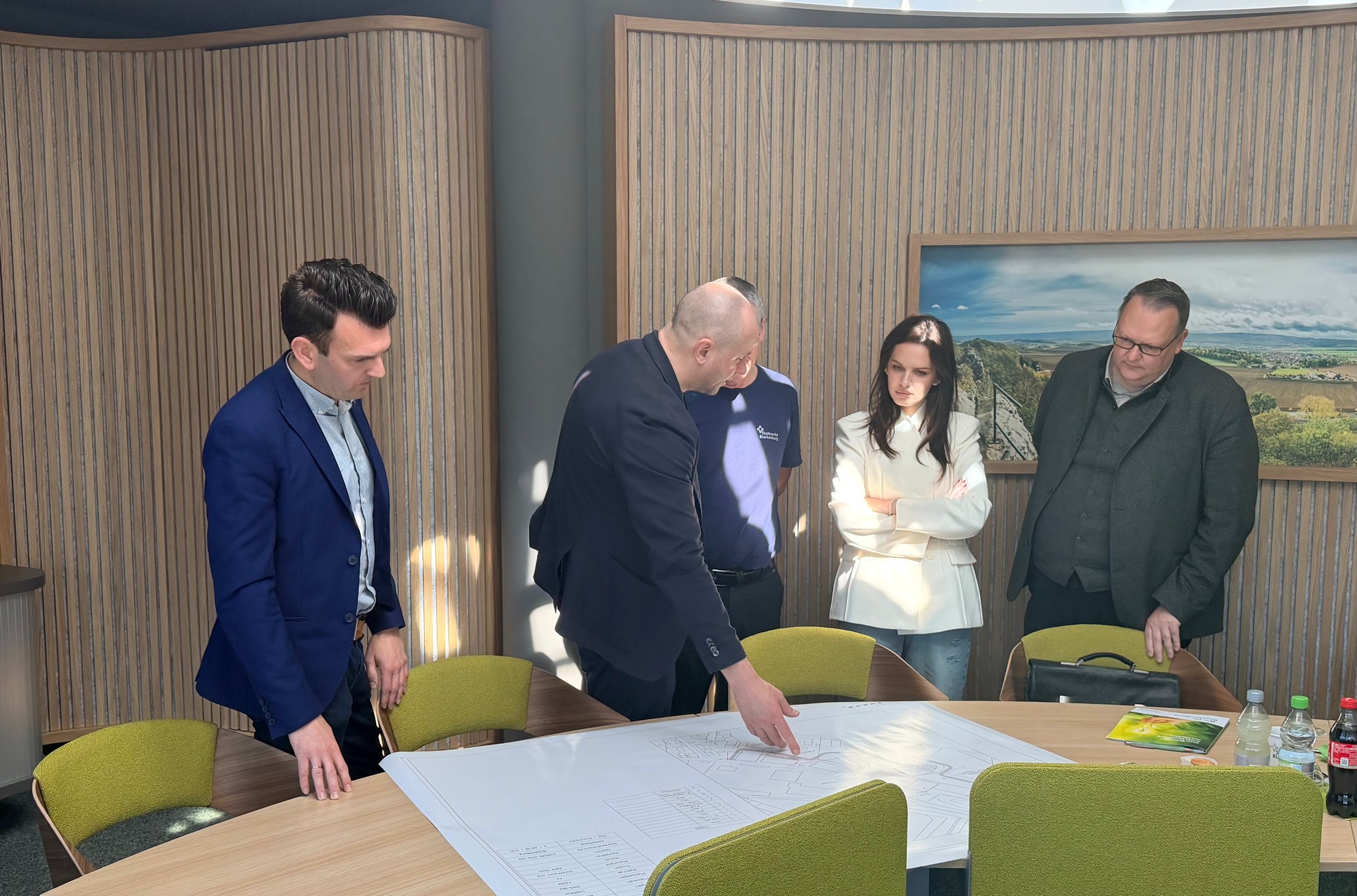 Five people around a table in Blankenburg town hall, a site plan of the campus spread out between them, one of them in a Stadtwerke Blankenburg shirt