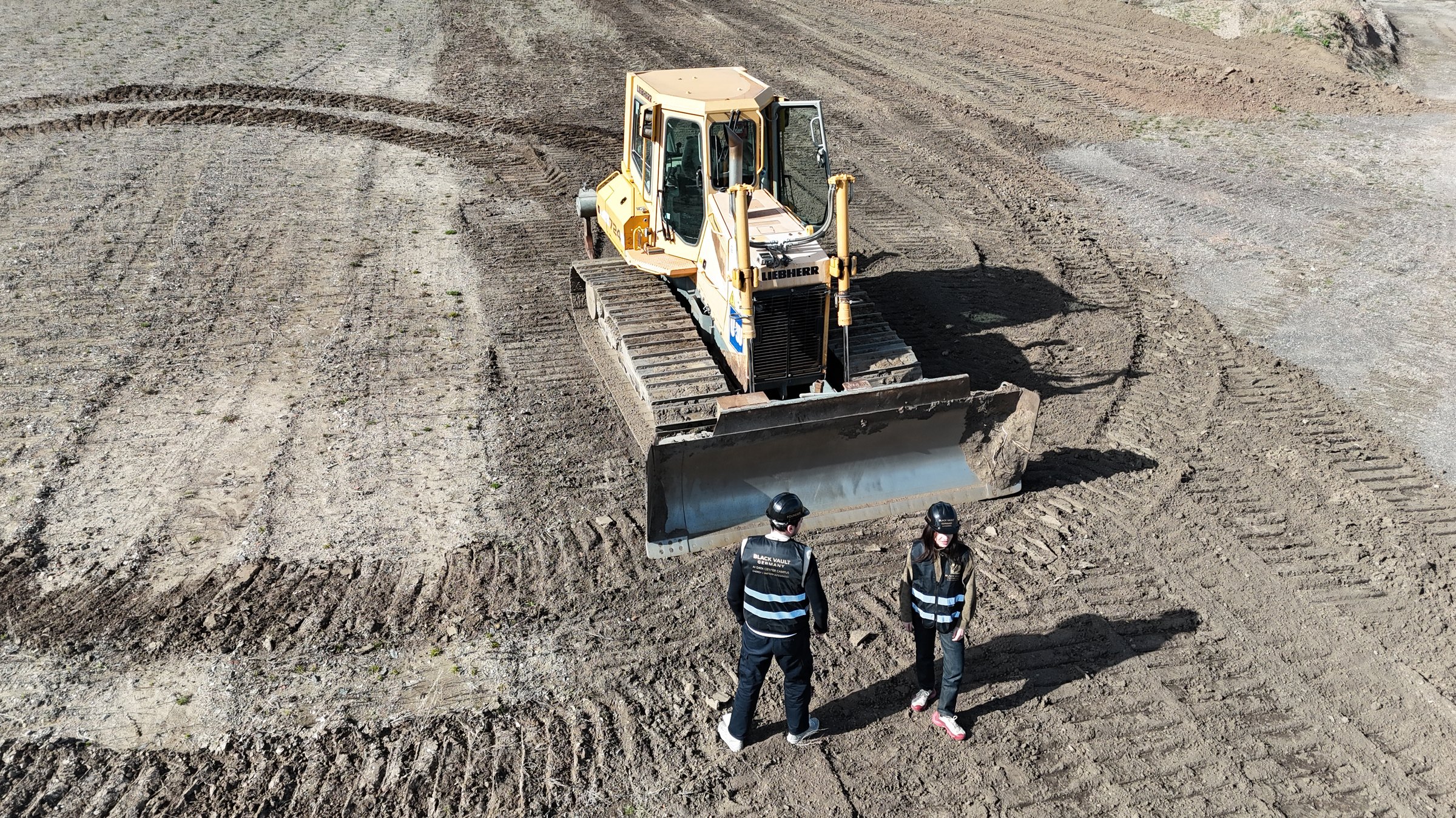 Two of the team on the cleared Blankenburg platform, seen from the air beside a tracked dozer