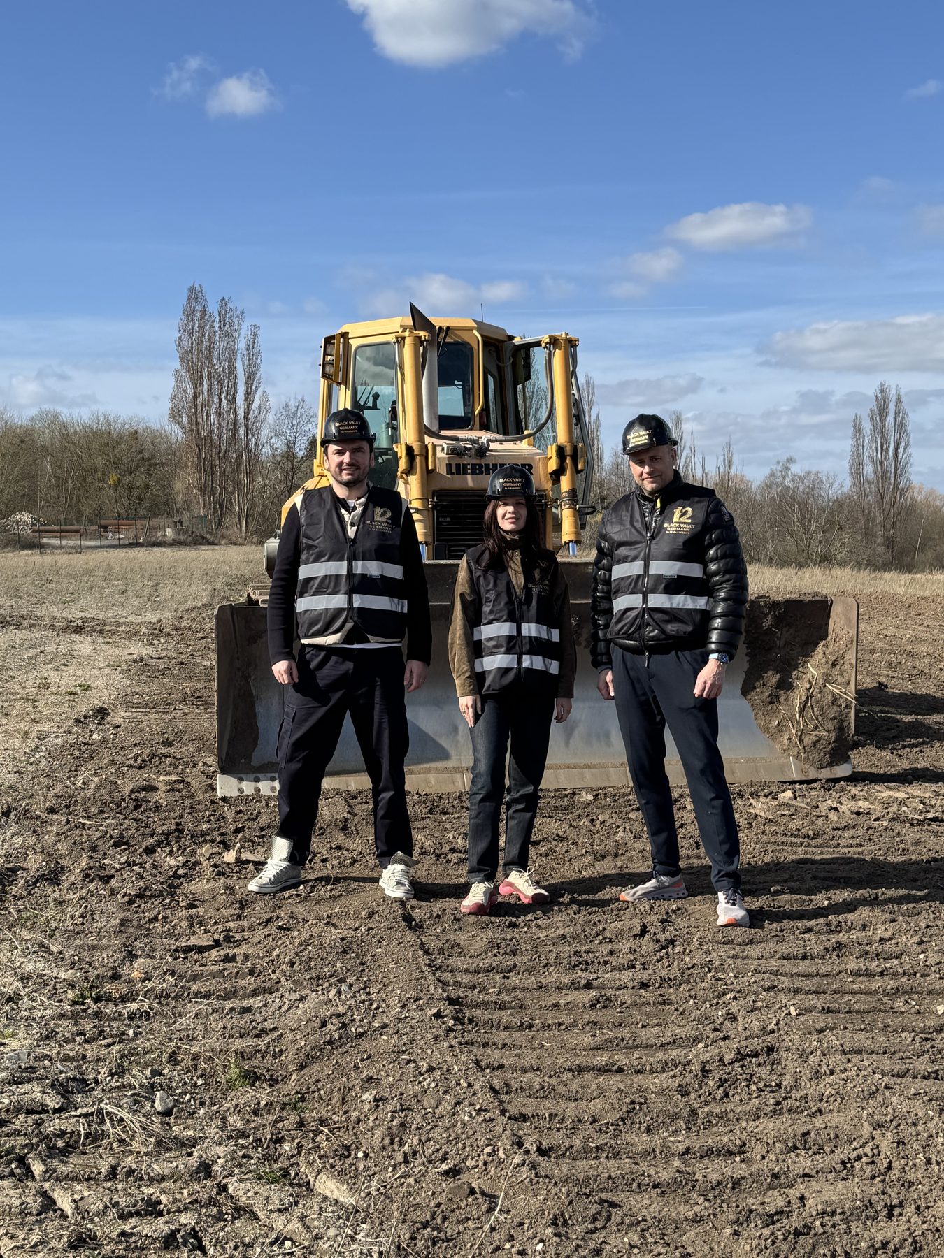 Denys Tsvaig, Anna Bon and Lars Gottschligg on the cleared platform at Blankenburg, a tracked dozer behind them