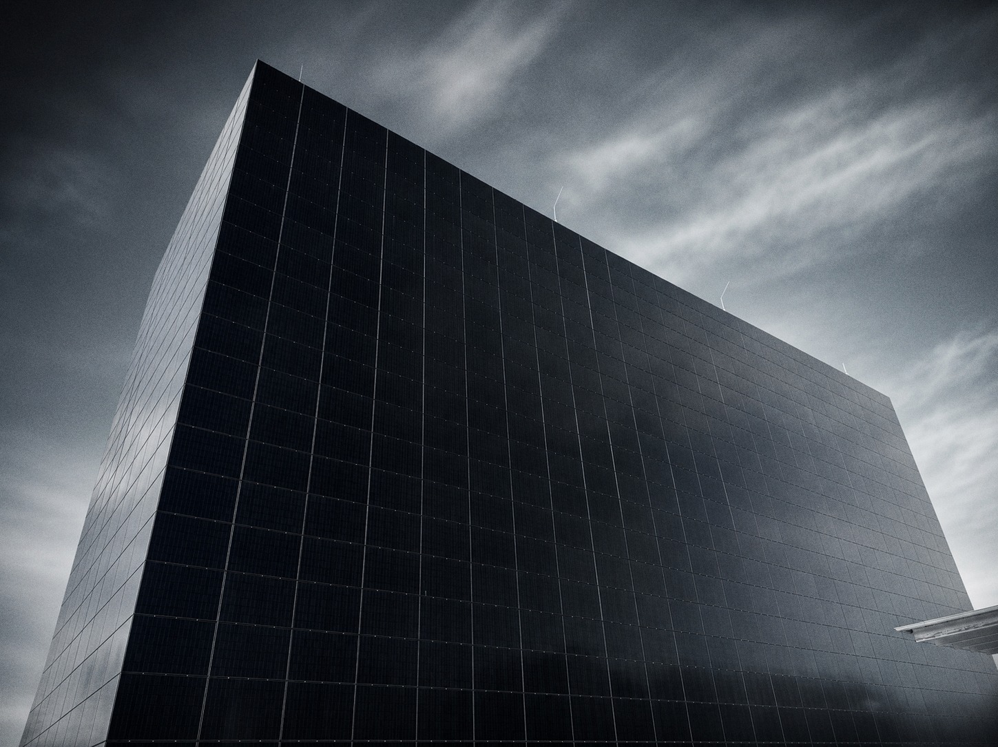 The Cube in Quedlinburg, low angle: the photovoltaic façade rising against a clouded sky