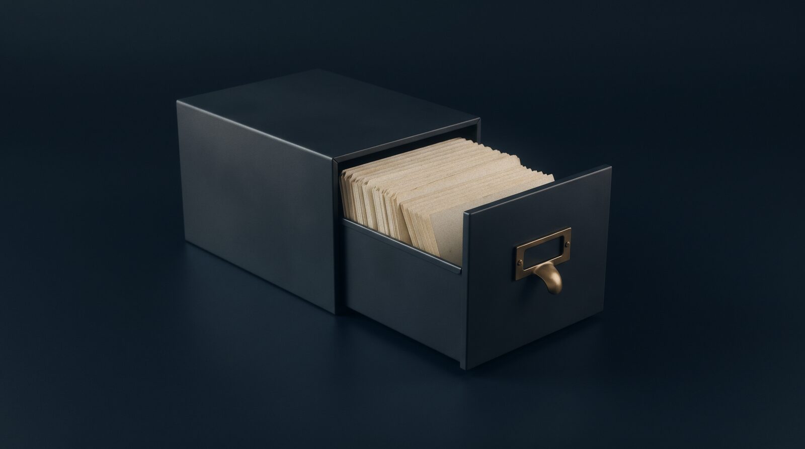 A dark card-index drawer pulled open, cream cards standing in it, a brass handle