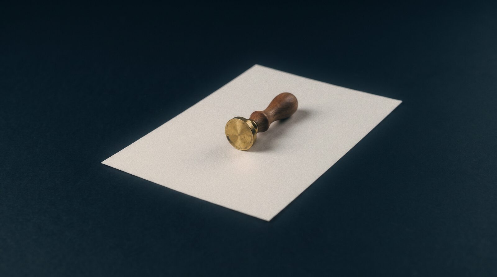 A brass embossing seal resting on a single sheet of pale paper
